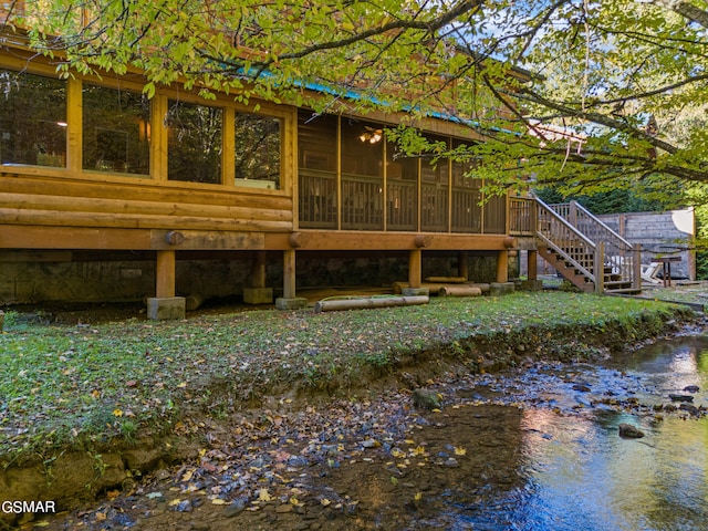 rear view of property featuring a sunroom and a water view