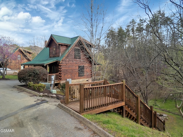 view of side of property with a deck, metal roof, and log exterior
