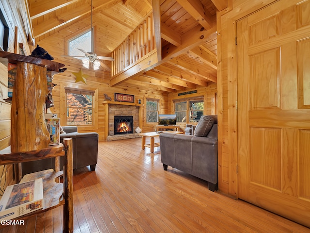 3416 Merlin Way, Pigeon Forge, TN 37863 - living room featuring wood walls, a wooden ceiling with exposed beams, light wood-type flooring, ceiling fan, and a stone fireplace