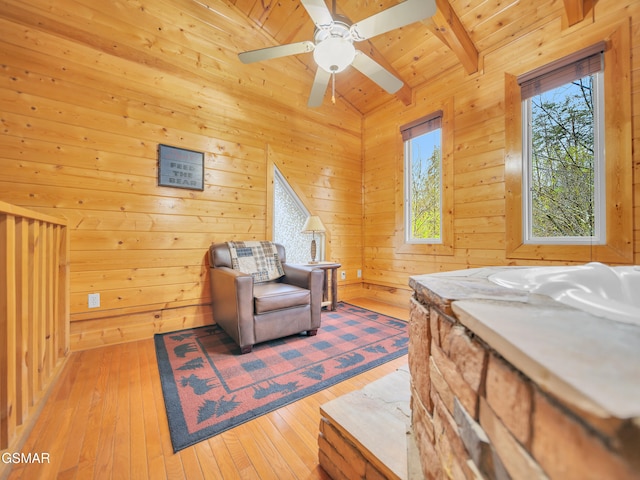 sitting room featuring beam ceiling, ceiling fan, wooden walls, wood ceiling, and hardwood / wood-style floors