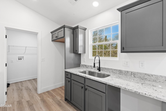 kitchen with light wood-type flooring, gray cabinets, and sink