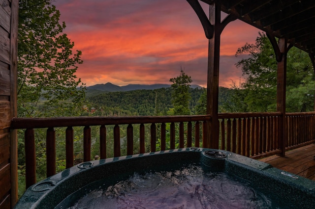 deck at dusk featuring a mountain view and a hot tub