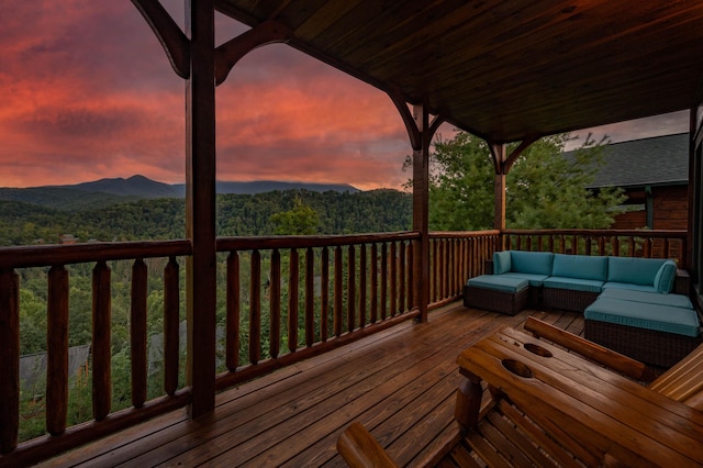 deck at dusk with an outdoor living space and a mountain view