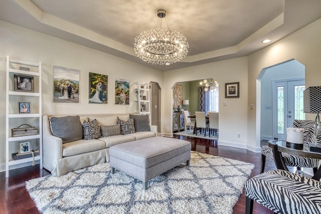 living room featuring a notable chandelier, dark hardwood / wood-style flooring, a wealth of natural light, and a tray ceiling