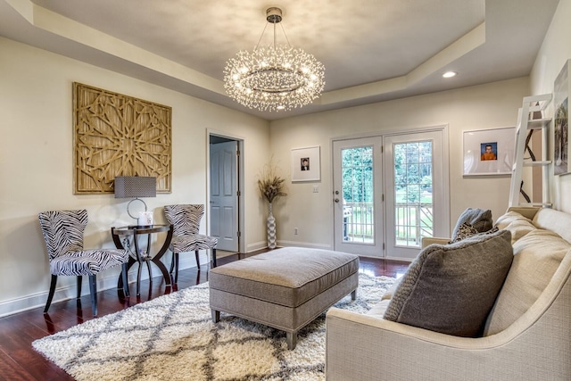 living area featuring a tray ceiling, a chandelier, and dark hardwood / wood-style floors