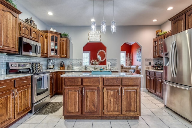 kitchen with a center island, light tile patterned floors, appliances with stainless steel finishes, and tasteful backsplash