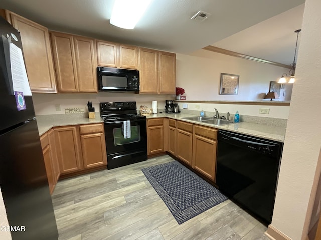 kitchen with black appliances, a sink, light wood-type flooring, and light countertops