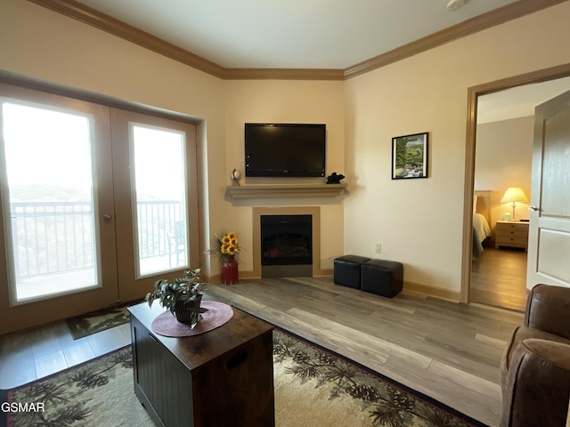 living area with wood finished floors, a fireplace, ornamental molding, french doors, and baseboards