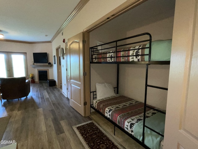 bedroom featuring crown molding, wood finished floors, and a fireplace
