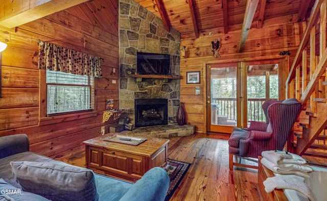 living room featuring beam ceiling, wooden walls, a fireplace, wood-type flooring, and wooden ceiling