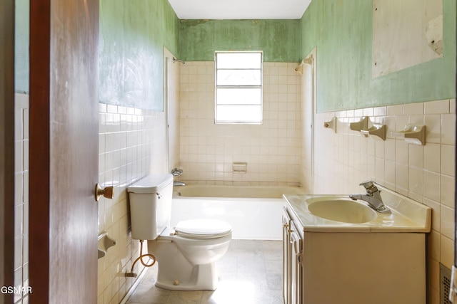 full bathroom with tiled shower / bath, vanity, tile walls, and toilet