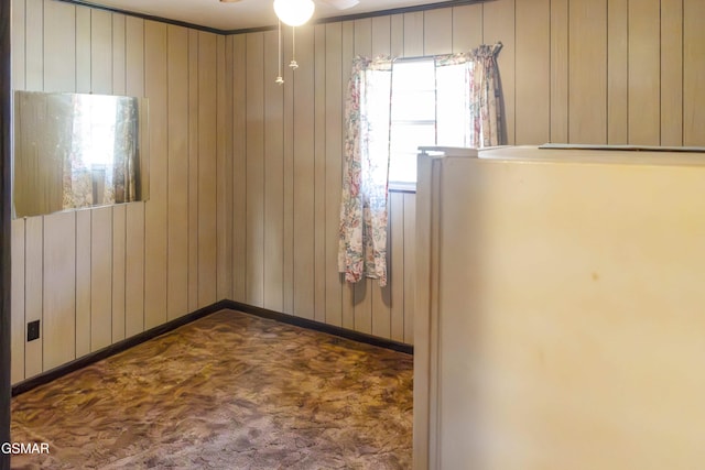 unfurnished room with ceiling fan and wood walls