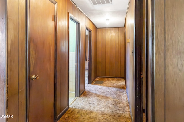 hall with wood walls and light carpet