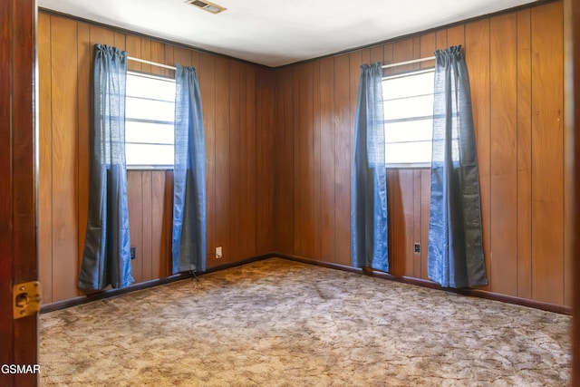 carpeted spare room with wooden walls