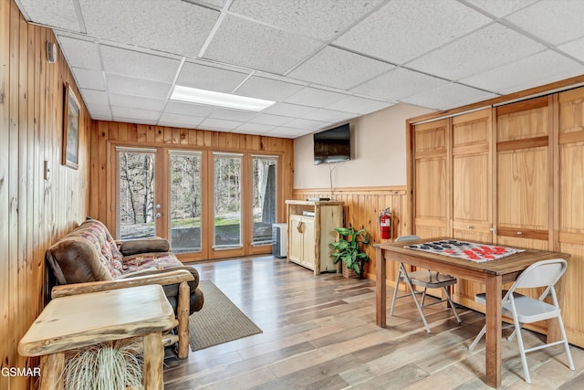 interior space featuring light wood-type flooring, wooden walls, and a paneled ceiling