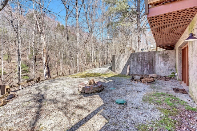 view of yard with a fire pit and a wooded view