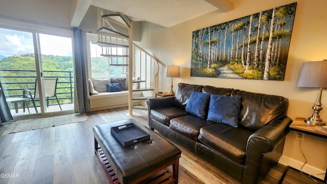 living room featuring beamed ceiling, wood-type flooring, a textured ceiling, and plenty of natural light