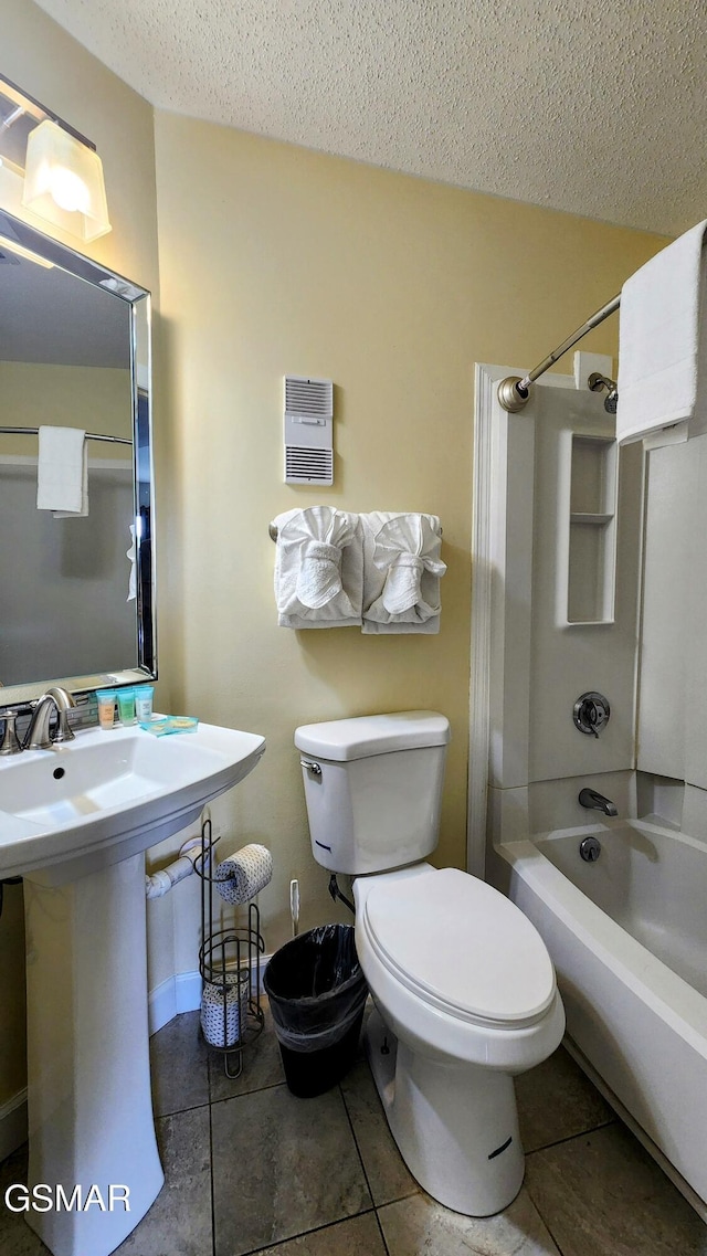 full bathroom with tile patterned floors, a textured ceiling, toilet, and shower / washtub combination