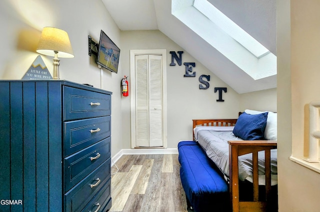 bedroom featuring vaulted ceiling with skylight, a closet, and hardwood / wood-style flooring