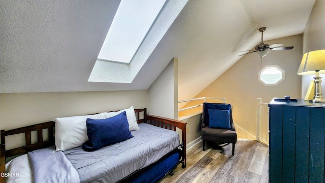 bedroom with hardwood / wood-style floors, ceiling fan, and lofted ceiling with skylight