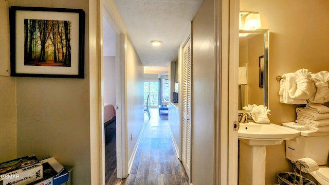 corridor with hardwood / wood-style flooring and a textured ceiling