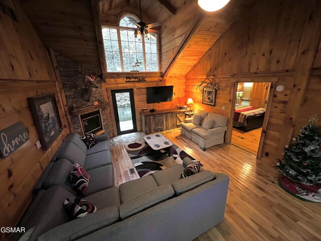 living room featuring wood walls, beamed ceiling, high vaulted ceiling, and hardwood / wood-style flooring