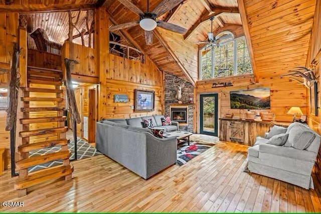 living room with hardwood / wood-style floors, high vaulted ceiling, ceiling fan, a fireplace, and beam ceiling