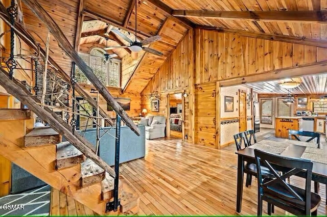 living room featuring beam ceiling, ceiling fan, wooden ceiling, wood walls, and hardwood / wood-style flooring