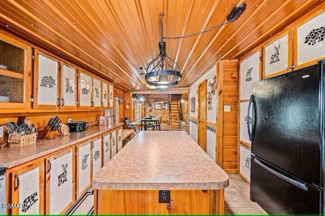 kitchen featuring a center island, decorative light fixtures, black refrigerator, light tile patterned floors, and wood ceiling