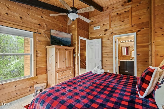 carpeted bedroom with beam ceiling, visible vents, ensuite bathroom, wood walls, and wooden ceiling