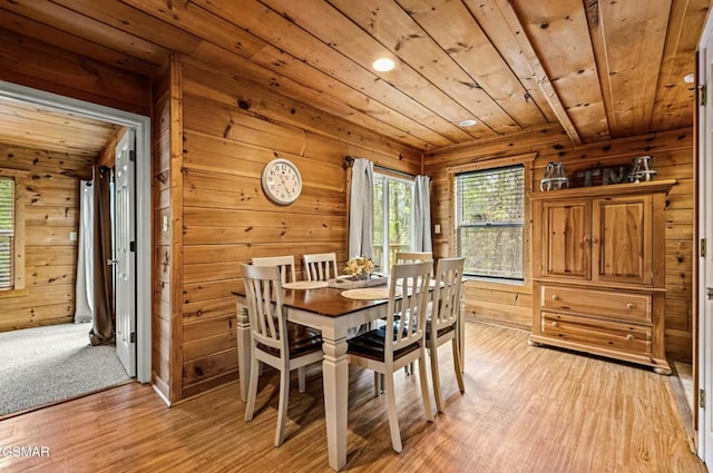 dining room featuring light wood-style floors, wood ceiling, and wood walls