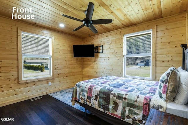 bedroom with visible vents, wood finished floors, wood ceiling, and wooden walls