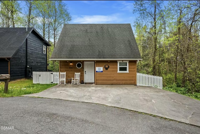 chalet / cabin featuring roof with shingles and fence