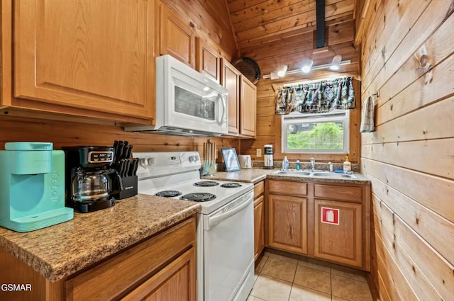 kitchen with light tile patterned floors, wooden ceiling, wooden walls, white appliances, and a sink