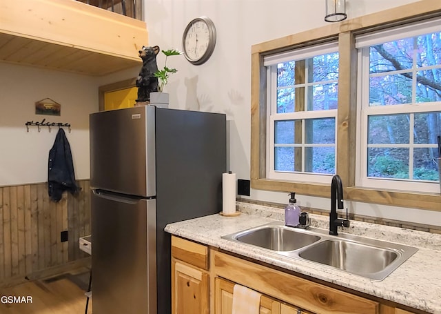 kitchen featuring light countertops, a sink, freestanding refrigerator, and a wainscoted wall