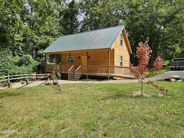 view of front facade featuring a porch, fence, a front lawn, and metal roof