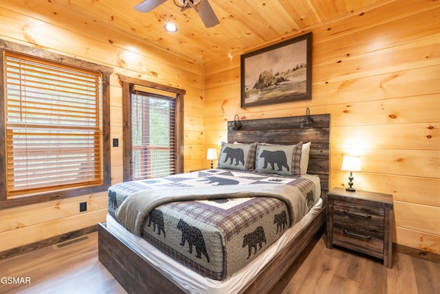 bedroom featuring ceiling fan, hardwood / wood-style floors, wooden walls, and wooden ceiling