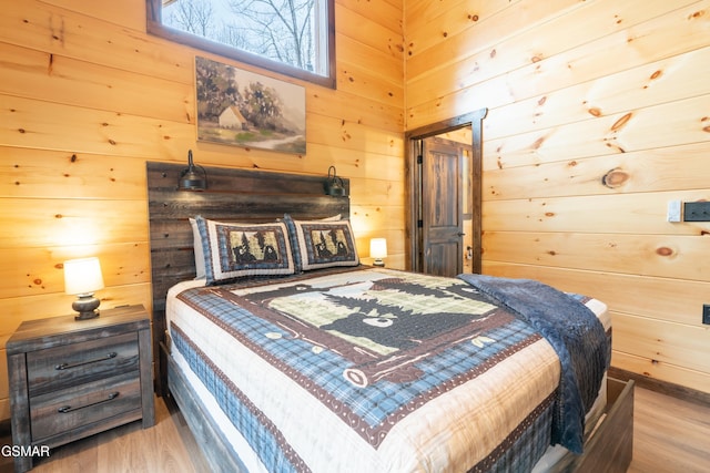 bedroom featuring light wood-type flooring and wood walls