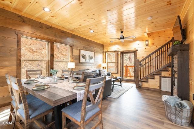 dining space with ceiling fan, wooden ceiling, and wood walls