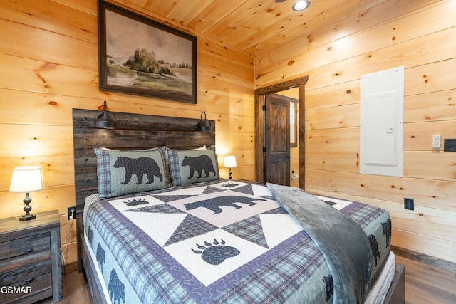 bedroom featuring dark wood-type flooring, wooden ceiling, electric panel, and wood walls