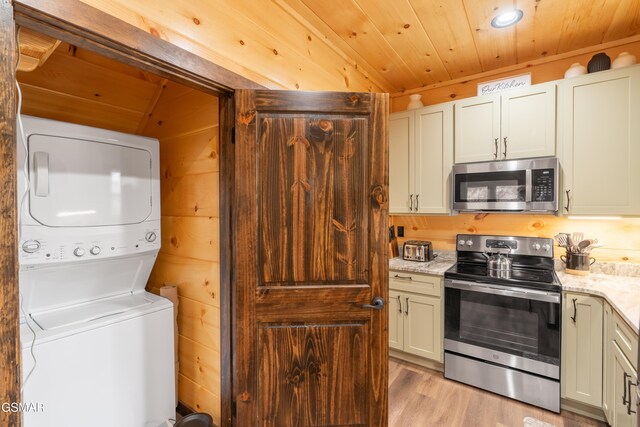 interior space with appliances with stainless steel finishes, stacked washer / drying machine, wood walls, light wood-type flooring, and wooden ceiling