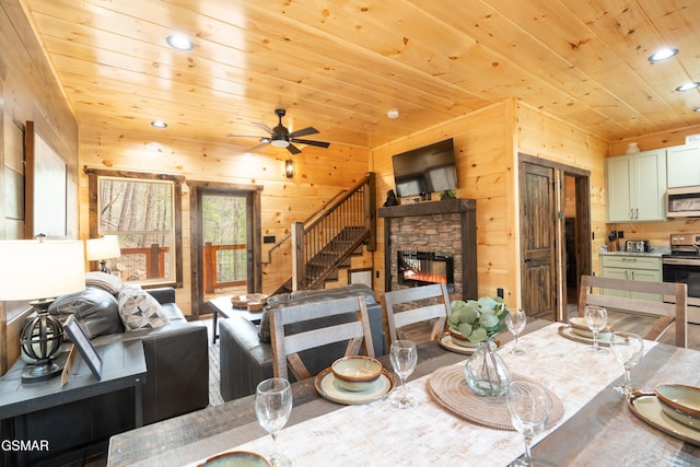 dining room with wood ceiling, wooden walls, and a stone fireplace