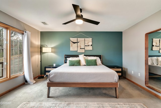 carpeted bedroom featuring a ceiling fan, visible vents, and baseboards