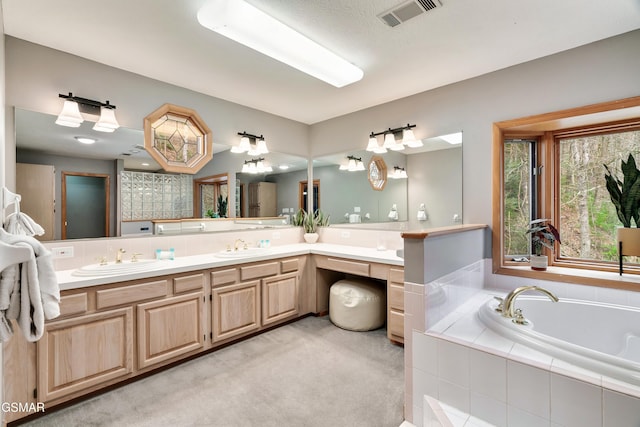 full bath featuring visible vents, a sink, a garden tub, and double vanity