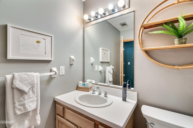 bathroom with toilet, vanity, and visible vents