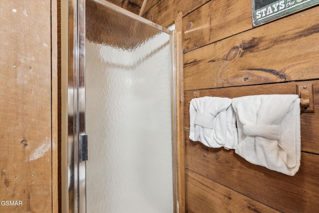 room details featuring a shower with shower door and wood walls