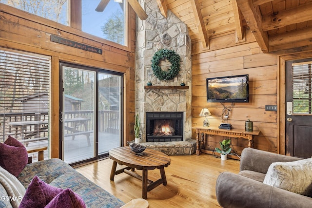 living room with a stone fireplace, wooden walls, wood-type flooring, wooden ceiling, and beam ceiling