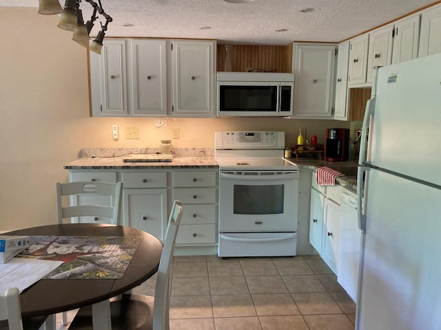 kitchen with light stone counters, a textured ceiling, white appliances, white cabinetry, and light tile patterned flooring