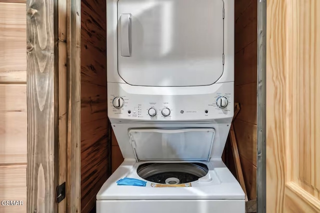 laundry room featuring laundry area, stacked washer and dryer, and wooden walls