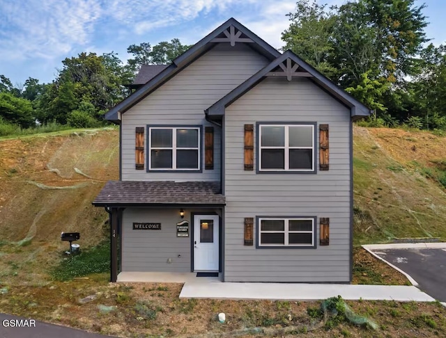 craftsman inspired home featuring a patio and roof with shingles